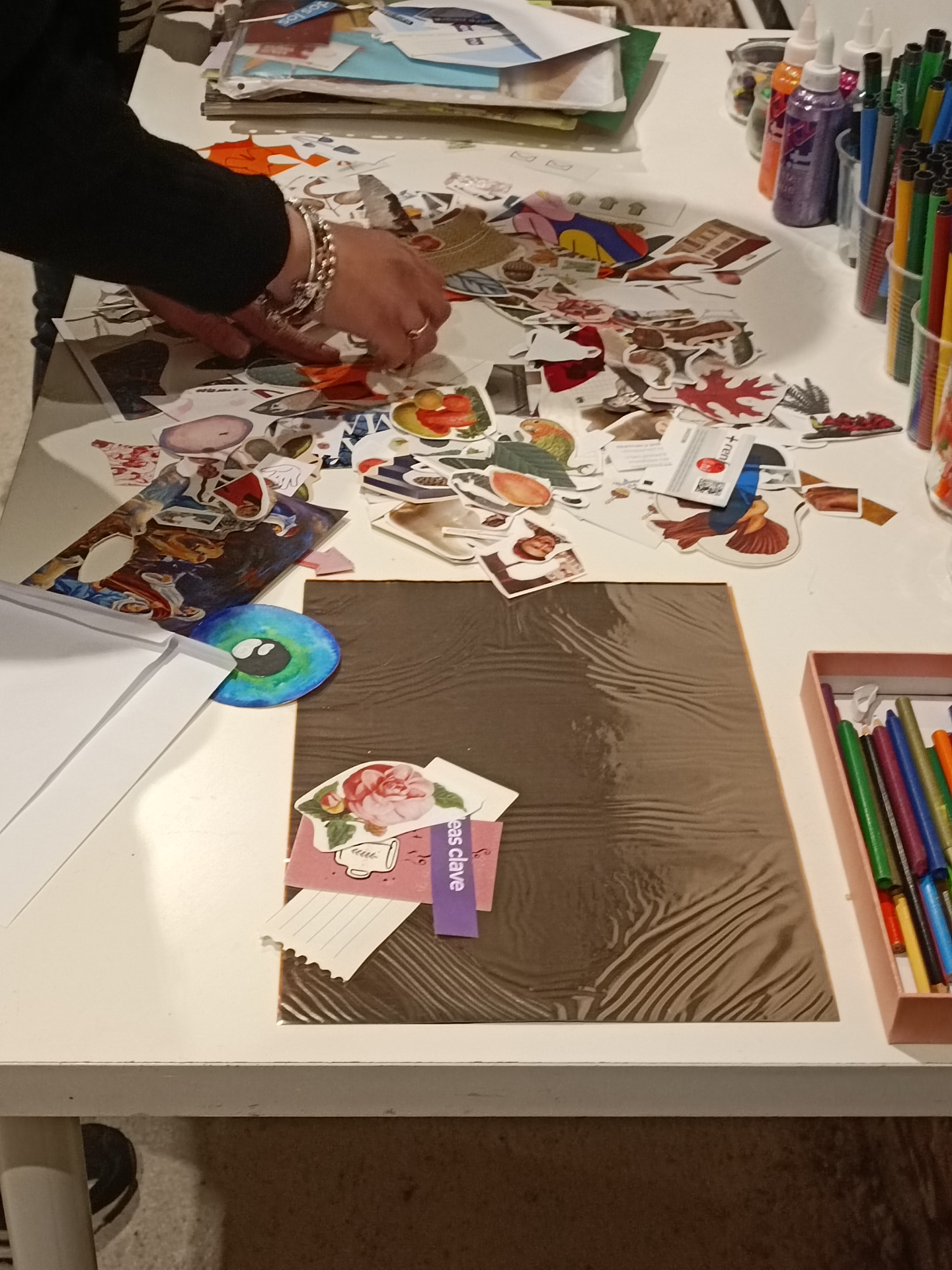 Mesa de taller con collage en proceso, recortes de revistas y rotuladores de colores